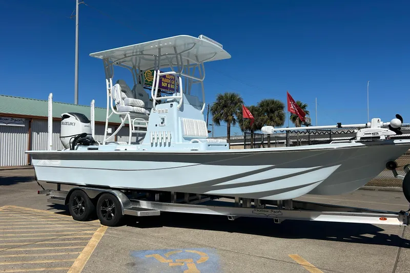 Slide: The Image of 2026 Shallow Sport 25 X3 boat on trailer, displayed outdoors under clear blue sky. - 2