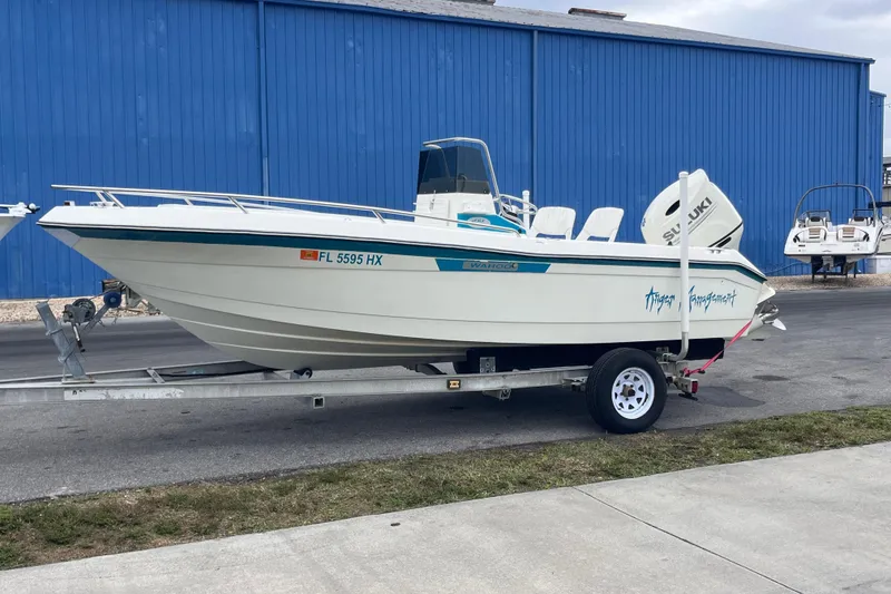 Slide: The Image of 1995 Wahoo 2100 EFS boat on trailer, parked near a blue building. - 1