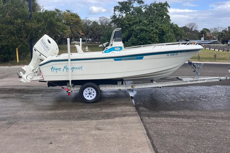 Slide: The Image of 1995 Wahoo 2100 EFS boat on trailer with Suzuki outboard motor, parked outdoors. - 2