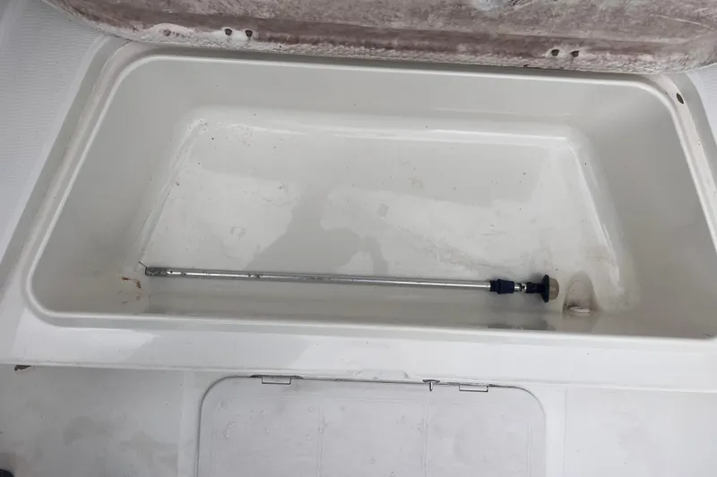 Slide: The Image of Open storage compartment in 1995 Wahoo 2100 EFS boat, featuring a metal rod inside. - 6