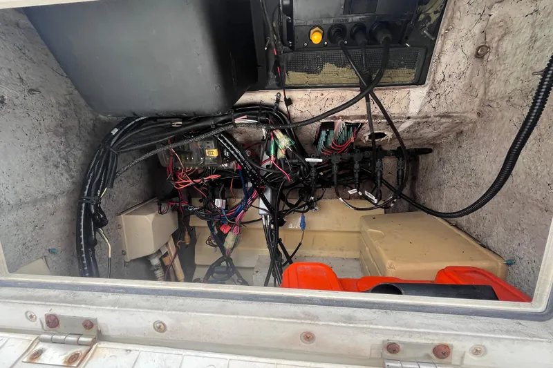 Slide: The Image of 1995 Wahoo 2100 EFS boat wiring and storage compartment with cables and containers. - 9