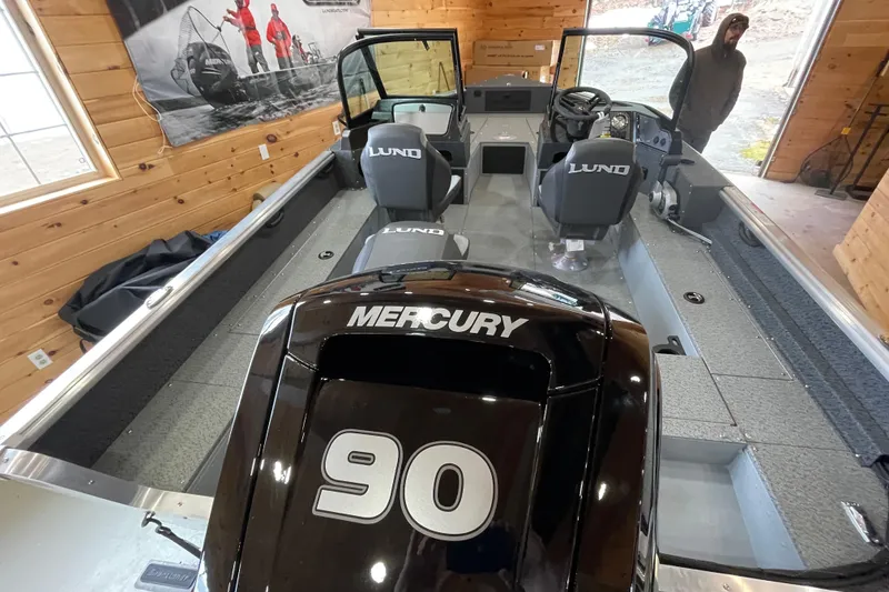 Slide: The Image of 2026 Lund 1700 Explorer Sport boat interior with Mercury 90 engine in a wooden showroom. - 7