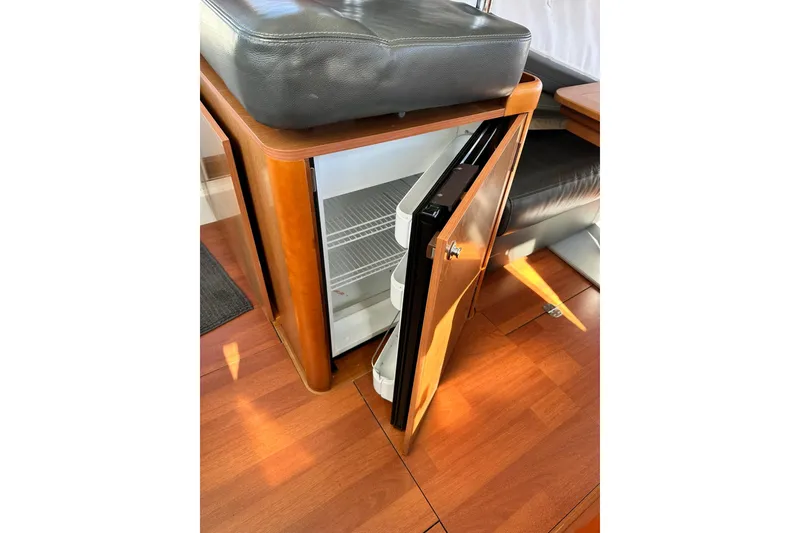 Slide: The Image of 2016 Beneteau Swift Trawler 34 interior with open mini fridge and wooden flooring. - 47