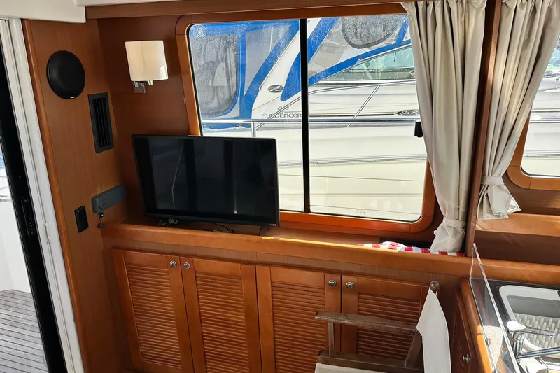 Slide: The Image of Interior of 2016 Beneteau Swift Trawler 34 with TV, wooden cabinets, and window view. - 48