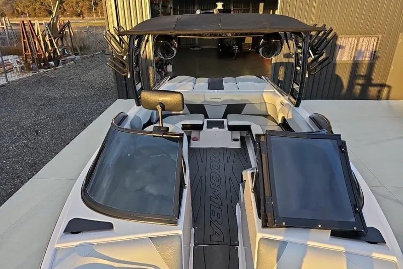 Slide: The Image of 2015 Moomba Mondo boat interior with seating and dashboard, docked near a warehouse. - 11