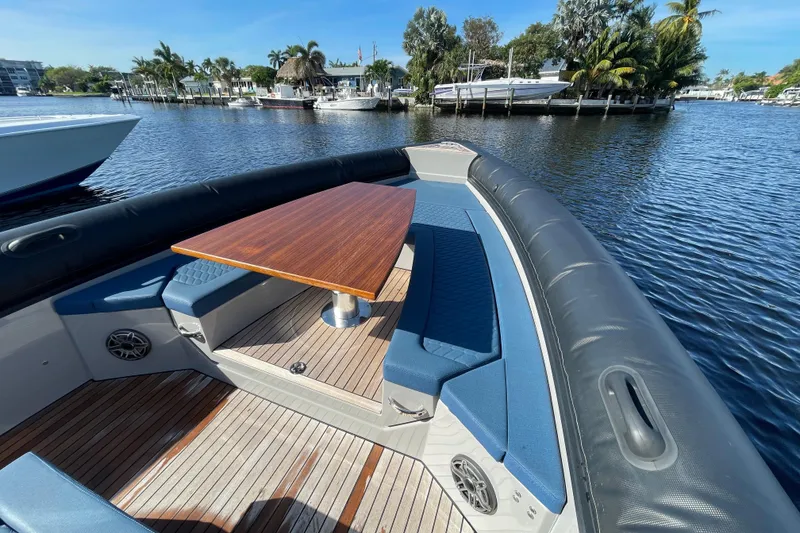 Slide: The Image of 2023 Skipper-BSK BSK 38 boat with wooden table and blue seating on calm water. - 18