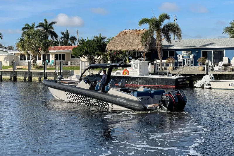 Slide: The Image of 2023 Skipper-BSK BSK 38 boat cruising near waterfront homes with palm trees. - 3