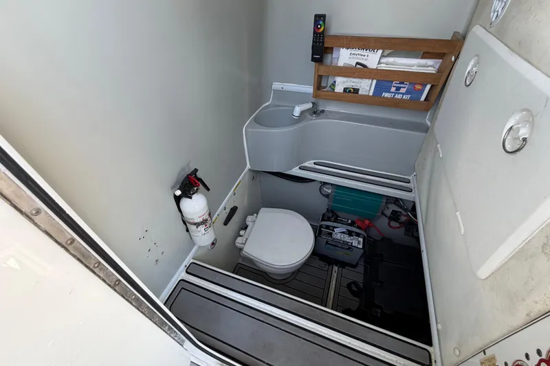 Slide: The Image of 2015 Contender 32 ST boat bathroom with toilet, sink, fire extinguisher, and first aid kit. - 32