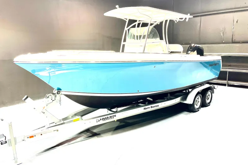 Slide: The Image of 2022 Sailfish 242 CC boat on trailer, blue hull, indoor setting. - 2