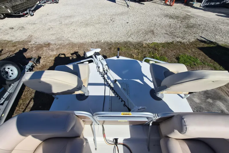 Slide: The Image of 2013 Hurricane FunDeck 226 boat with beige seating and trolling motor, parked on gravel. - 11