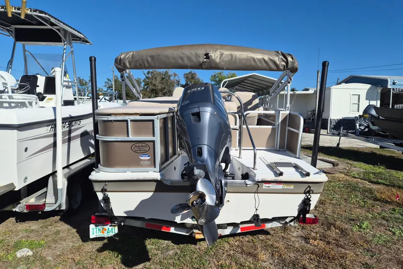 Slide: The Image of 2013 Hurricane FunDeck 226 boat with outboard motor, parked on grass under clear blue sky. - 4