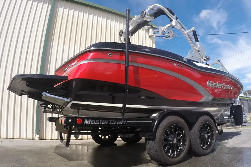 Slide: The Image of 2017 MasterCraft X10 boat in vibrant red on a trailer, parked outdoors. - 5