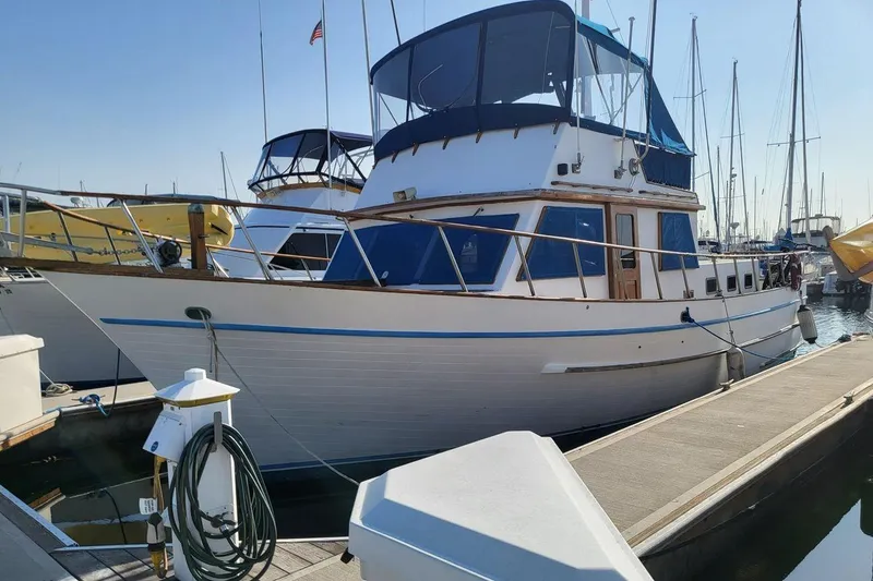 The Image of 1981 Marine Trader trunk cabin trawler docked at marina, featuring blue accents and upper deck. - 0