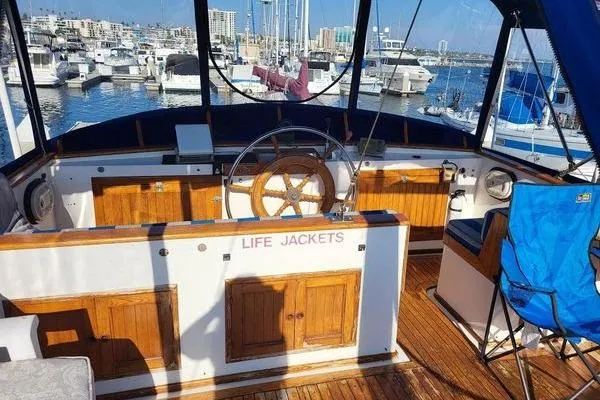 Slide: The Image of 1981 Marine Trader trunk cabin trawler interior with wooden helm, marina view, and life jackets. - 1
