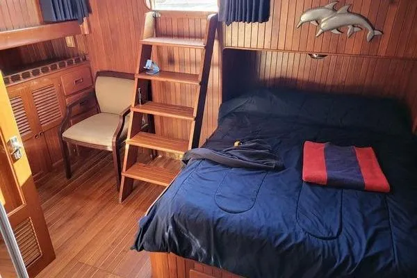 Slide: The Image of 1981 Marine Trader trunk cabin trawler interior with bed, wooden decor, and ladder. - 2