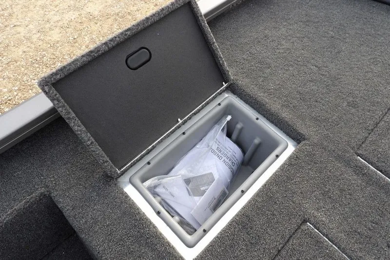 Slide: The Image of 2026 Crestliner XFC 189 boat storage compartment with open lid and documents inside. - 10