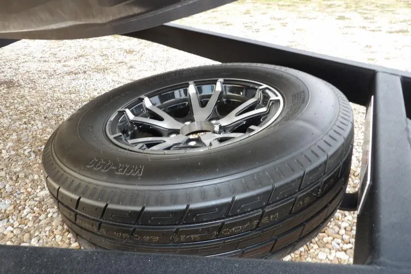 Slide: The Image of Spare tire on a 2026 Crestliner XFC 189 trailer, resting on gravel. - 44