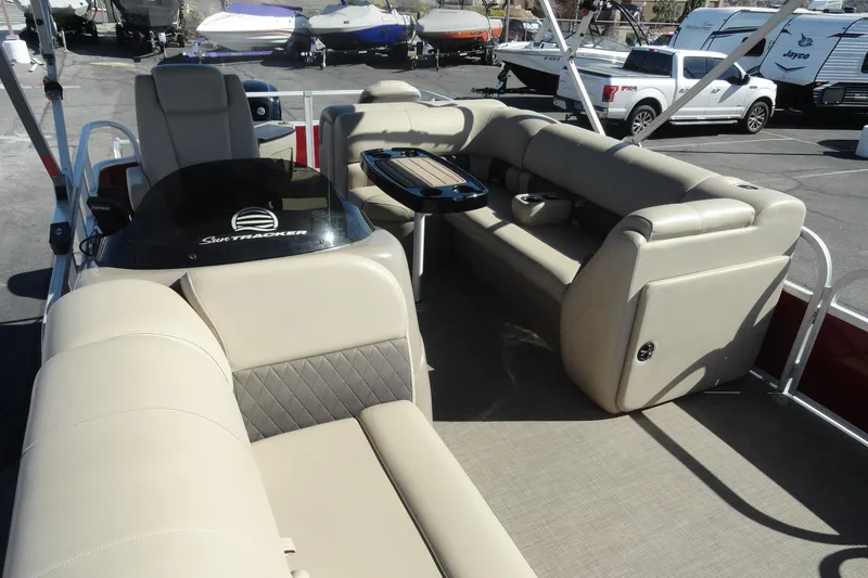 Slide: The Image of 2022 Sun Tracker Fishin' Barge 20 DLX interior with beige seating and table. - 18