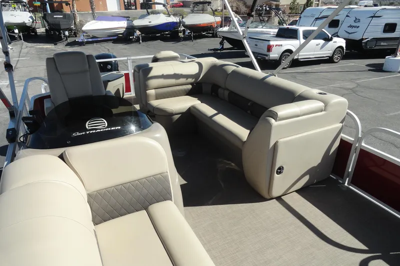 Slide: The Image of 2022 Sun Tracker Fishin' Barge 20 DLX with beige seating in a boat dealership. - 19