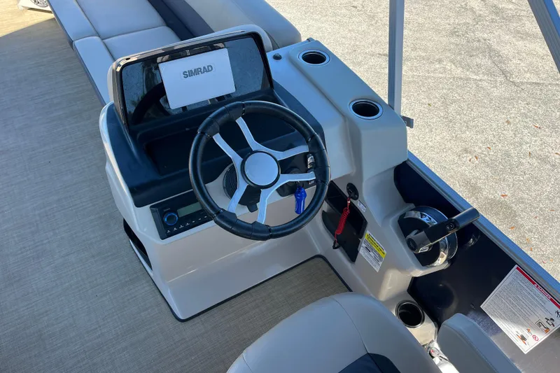 Slide: The Image of 2024 Harris Cruiser 230 boat dashboard with steering wheel and Simrad display. - 18