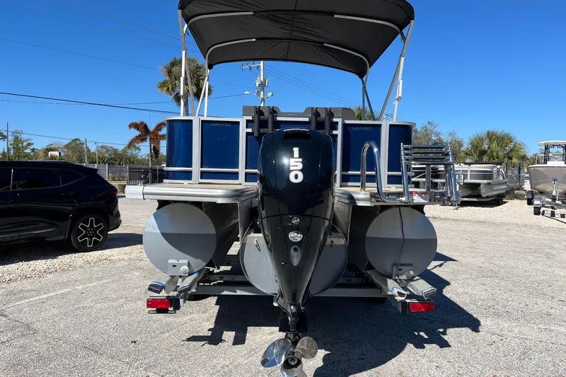 Slide: The Image of 2024 Harris Cruiser 230 pontoon boat with 150 HP engine, parked outdoors. - 4