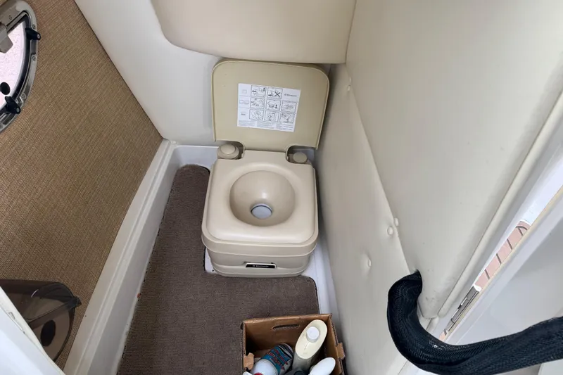 Slide: The Image of Portable toilet inside a 2011 Cobalt 242 boat, with storage and cleaning supplies. - 12