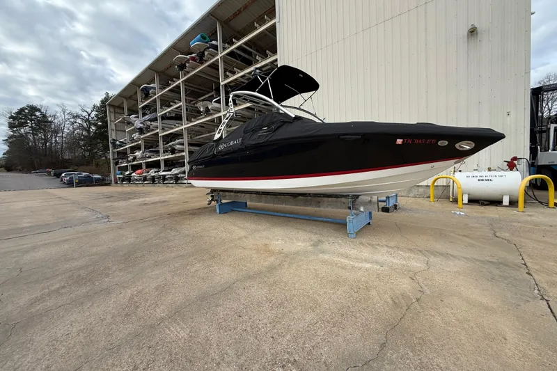 Slide: The Image of 2011 Cobalt 242 boat on stand near storage facility, overcast sky. - 6