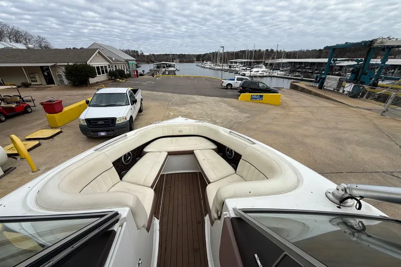 Slide: The Image of 2011 Cobalt 242 boat at marina with docked boats and vehicles in background. - 7