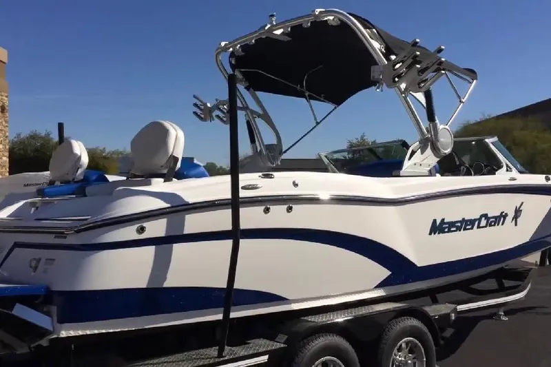 Slide: The Image of 2018 MasterCraft X46 boat with sleek design and blue accents on a trailer. - 2