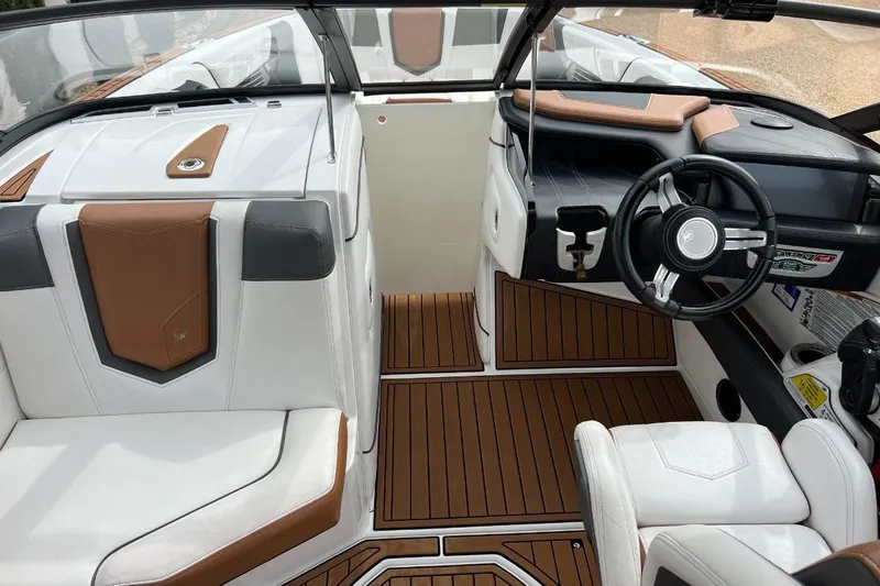 Slide: The Image of 2018 Nautique Super Air Nautique G23 interior with brown and white seating, sleek dashboard, and steering wheel. - 9