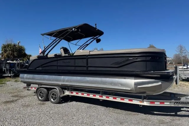 The Image of 2024 Barletta CORSA 25 QSSA pontoon boat on a trailer, under clear blue sky. - 1