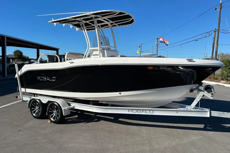 The Image of 2016 Robalo R200 Center Console boat on trailer, black hull, sunny day. - 1
