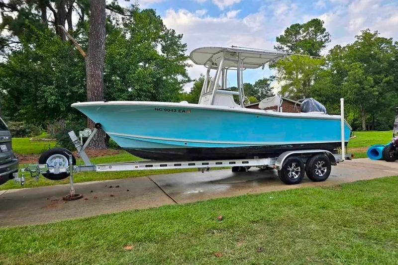 The Image of 2015 Sea Hunt Ultra 211 boat on trailer, parked outdoors with trees in background. - 1