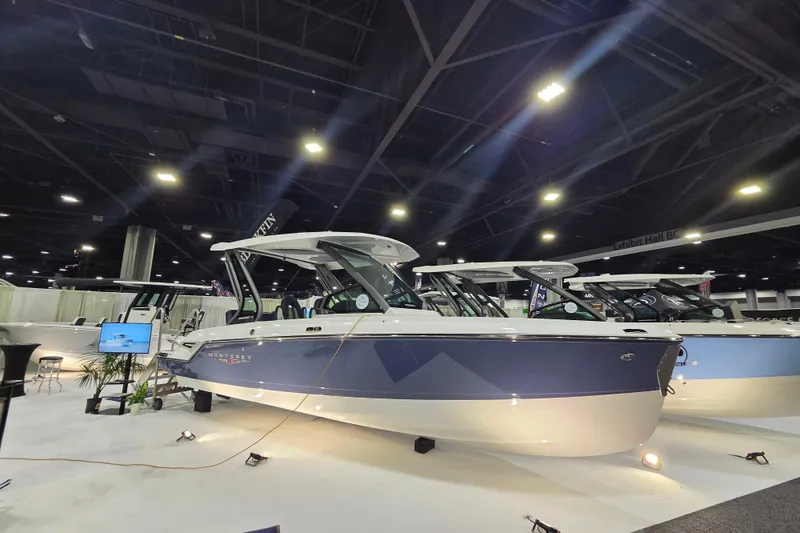 Slide: The Image of 2026 Monterey Elite 25 SD boat displayed at an indoor exhibition, under bright lighting. - 3