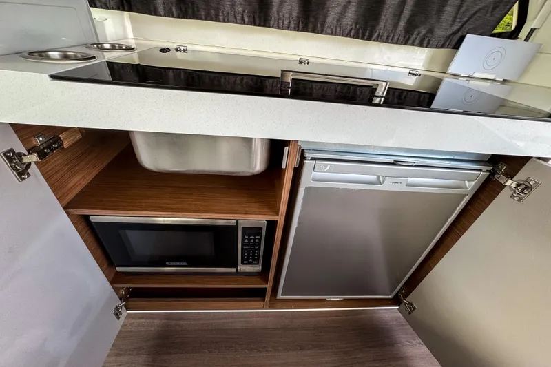 Slide: The Image of 2024 Beneteau Antares 11 kitchen with sink, microwave, and fridge. - 19