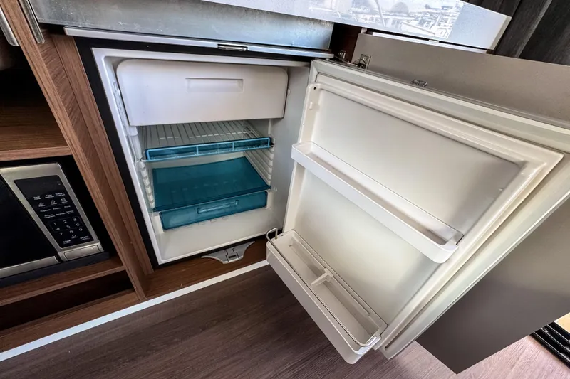 Slide: The Image of Open refrigerator inside 2024 Beneteau America Antares 11 boat, showcasing interior storage space. - 20