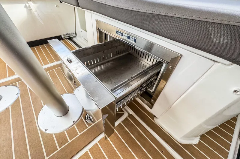 Slide: The Image of 2024 Beneteau Antares 11 boat interior with open stainless steel drawer on wooden deck. - 7