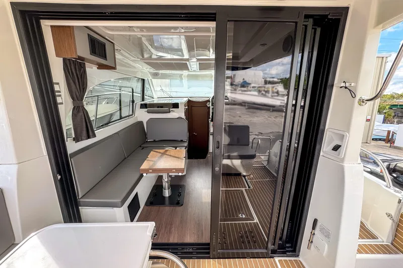 Slide: The Image of 2024 Beneteau America Antares 11 interior with seating and table, viewed through sliding glass doors. - 9