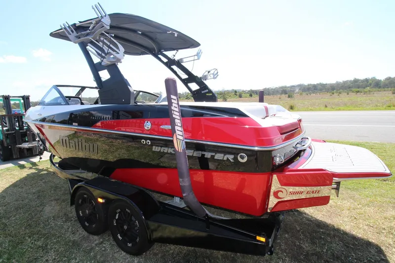 Slide: The Image of 2018 Malibu Wakesetter 20 VTX boat on trailer, red and black design, parked outdoors. - 2