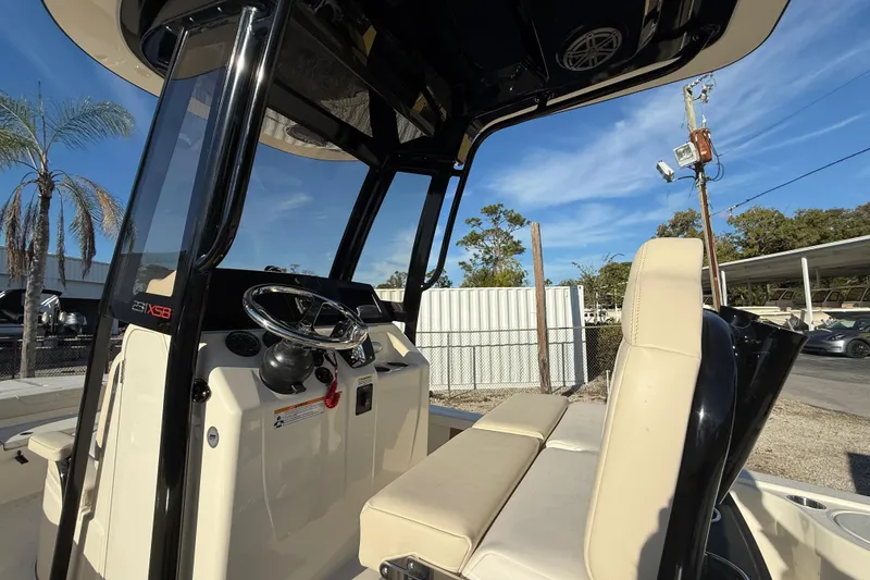 Slide: The Image of 2026 Scout 231 XSB boat interior with steering wheel and seating, under clear blue sky. - 3