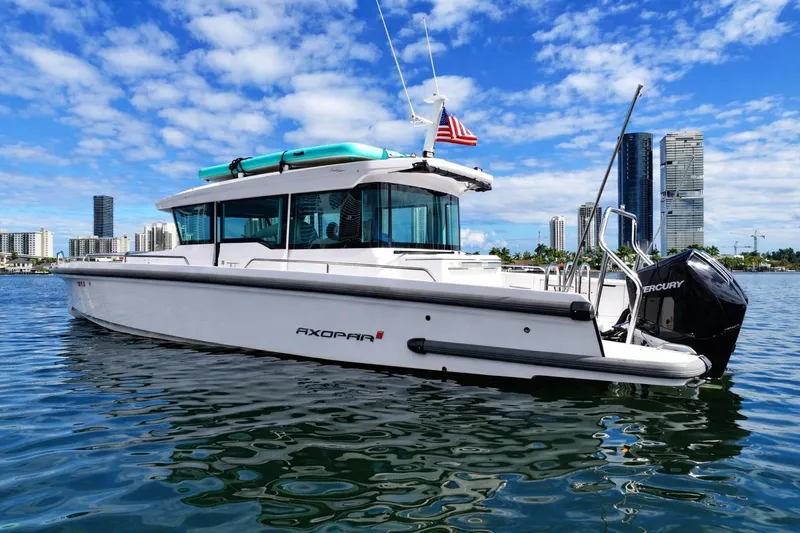 Slide: The Image of 2022 Axopar 37 XC Cross Cabin boat on water, city skyline background. - 2