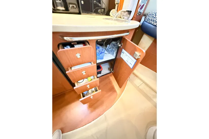 Slide: The Image of 2004 Chaparral Signature 350 interior with open wooden cabinets and drawers in the kitchen area. - 25