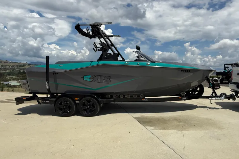 Slide: The Image of 2022 Axis T220 boat on trailer under cloudy sky, side view. - 2