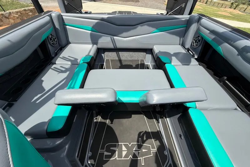 Slide: The Image of 2022 Axis T220 boat interior with gray and teal seating, featuring cup holders and speakers. - 4