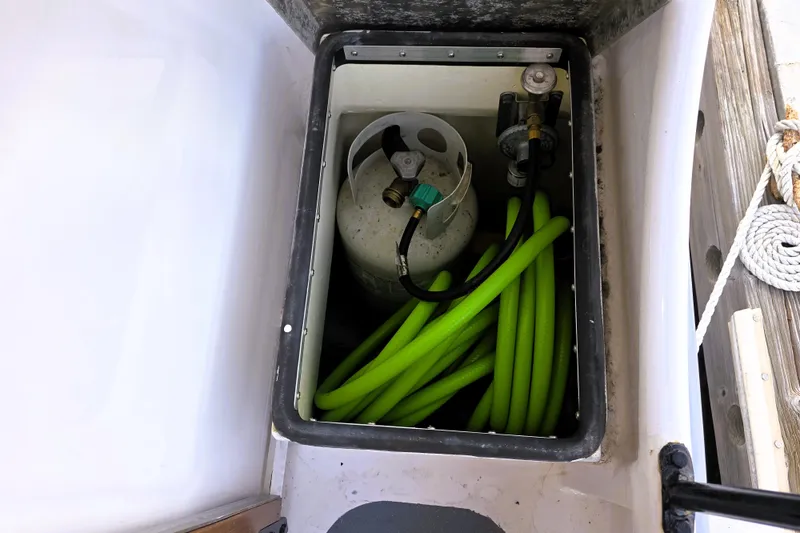 Slide: The Image of Storage compartment in 2016 Custom 25 Tug with propane tank and green hose. - 17