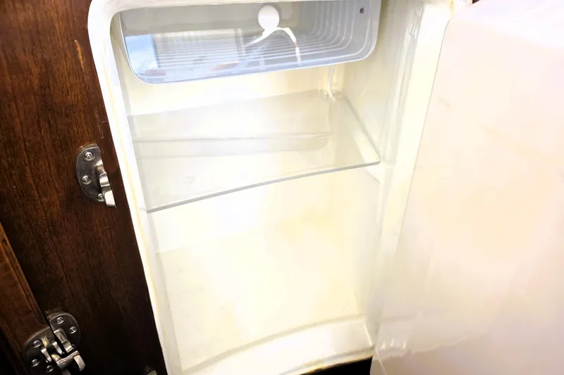 Slide: The Image of Open refrigerator inside a 2016 Custom 25 Tug boat, featuring wooden door and metal latch. - 40