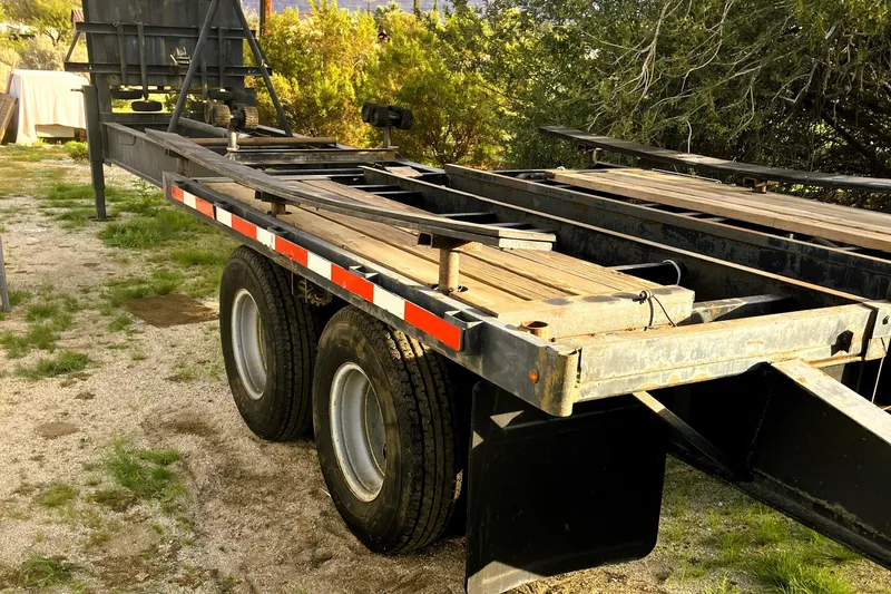 Slide: The Image of 2016 Custom 25 Tug trailer with dual wheels, parked on gravel near greenery. - 62
