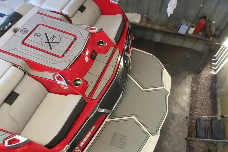 Slide: The Image of 2022 MasterCraft X24 boat interior with red and gray seating, viewed from above. - 2