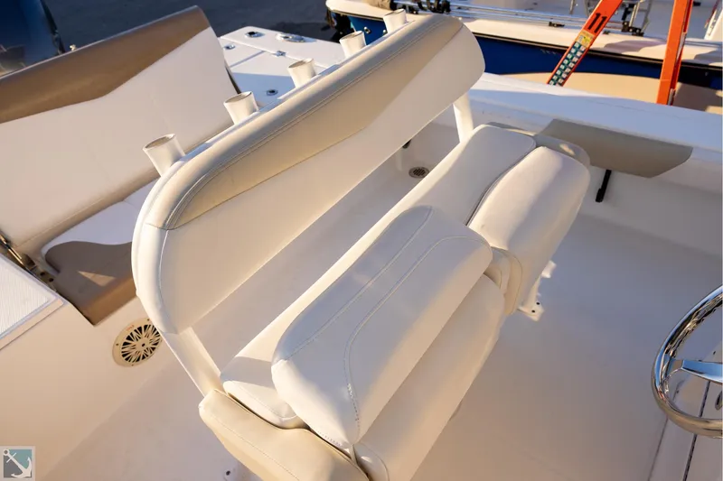 Slide: The Image of 2016 Robalo 246 Cayman boat interior with white cushioned seating and rod holders. - 12