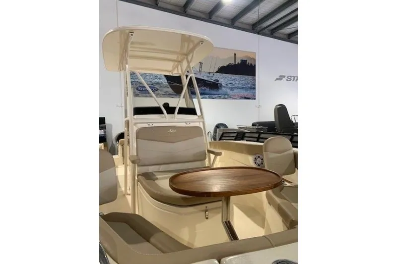 Slide: The Image of 2022 Scout 215 XSF boat interior with seating and wooden table in showroom. - 3